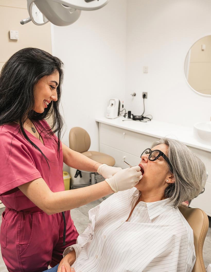 What to Expect at Your Dental Exam Dentist examining an older patient’s mouth while she reclines in a dental chair