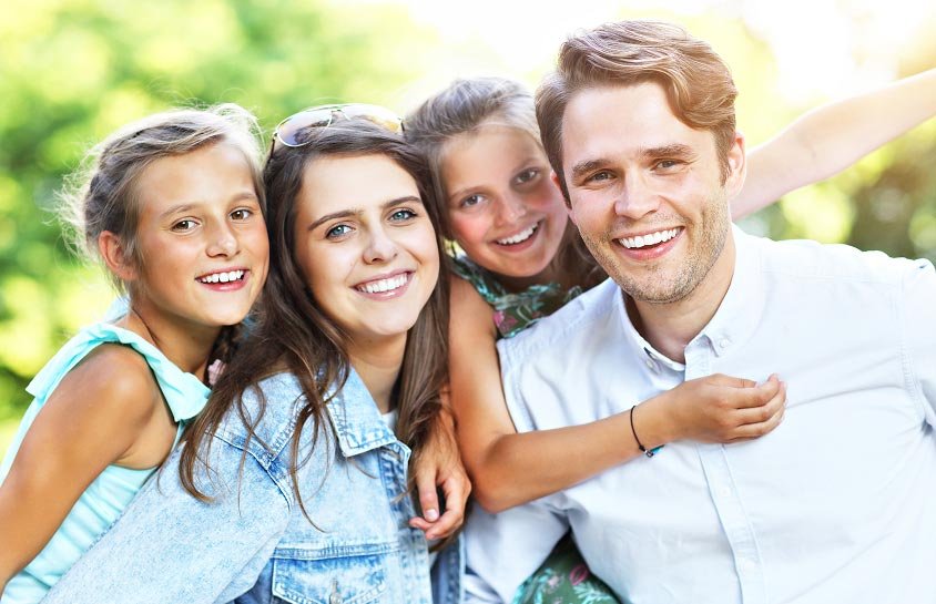 Smiling parents with their two daughters outdoors