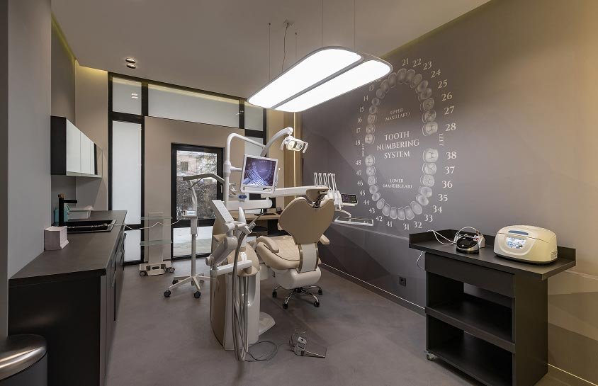 Dental treatment room with a dental chair, overhead light, and equipment