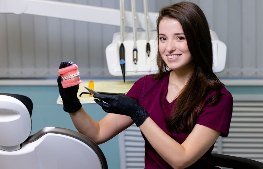 Dental Exams in Winter Springs, FL Dental professional holding a tooth model and mirror in a dental clinic