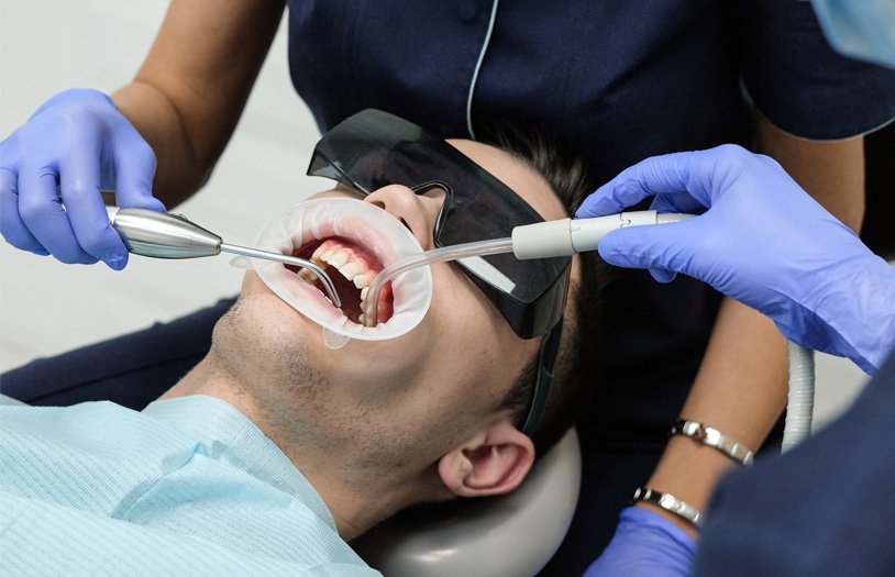 Patient wearing protective glasses while a dental professional cleans his teeth